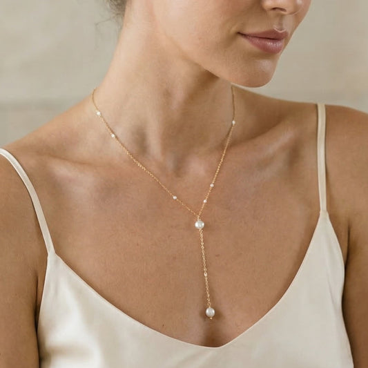 Woman wearing a delicate necklace with a neutral background